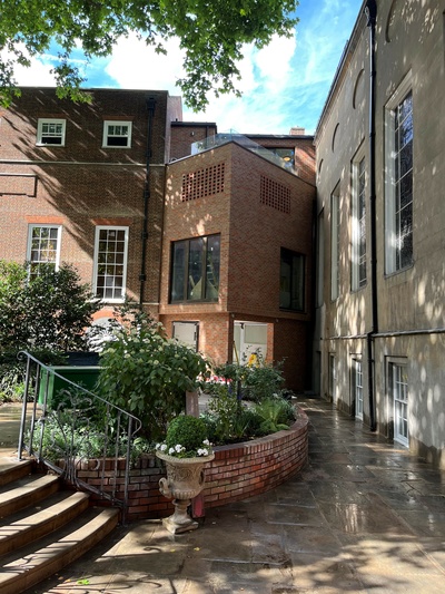 Photograph showing part of Stationers' Hall garden with the new Link Building, joining the main Hall and Court Room. The exterior of the new building is chamfered, in contrast to the flat exteriors of the adjacent buildings. The design gives space for a reception area in front of the newly inserted lift shaft, providing full step-free access to the Hall..