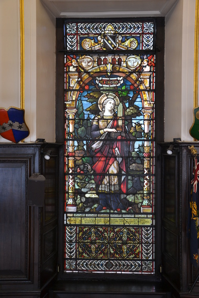Stained glass window featuring a winged and haloed woman holding a portative organ.