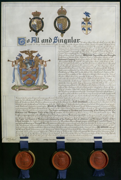 A scroll with ornate calligraphy and three wax seals hanging from the lower edge, issued by the College of Arms. Across the header of the document are the arms of the Monarch, the Earl Marshal and the College of Arms in London. The arms of the Company of Stationers and Newspaper Makers are shown in the main part of the document. Heraldic description of the arms: Azure, on a chevron between three books with clasps, an eagle volant gules with a nimbus, between two roses gules leaved vert. In chief issuing out of a cloud proper radiates a Holy Spirit, wings displayed, argent with a nimbus. On either side an angel proper, vested argent, mantled azure, winged and blowing a trumpet. Motto: Verbum Dei manet in aetemum (the Word of God lasts forever)